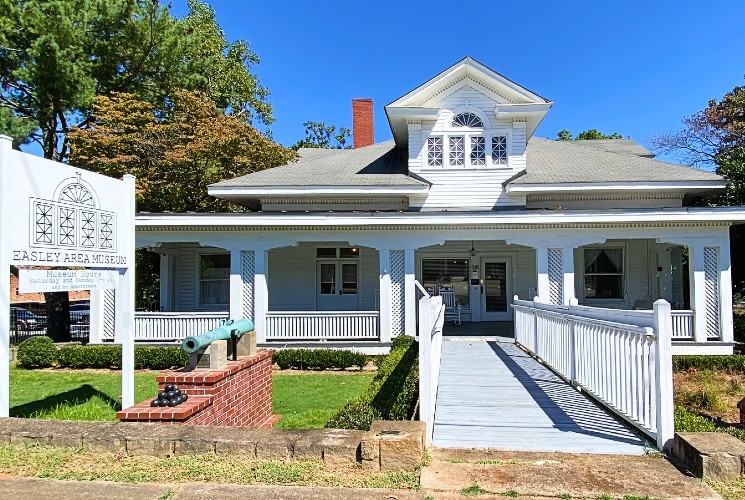 Front facade of a historical museum with wrap around porch and long walkway to the front door