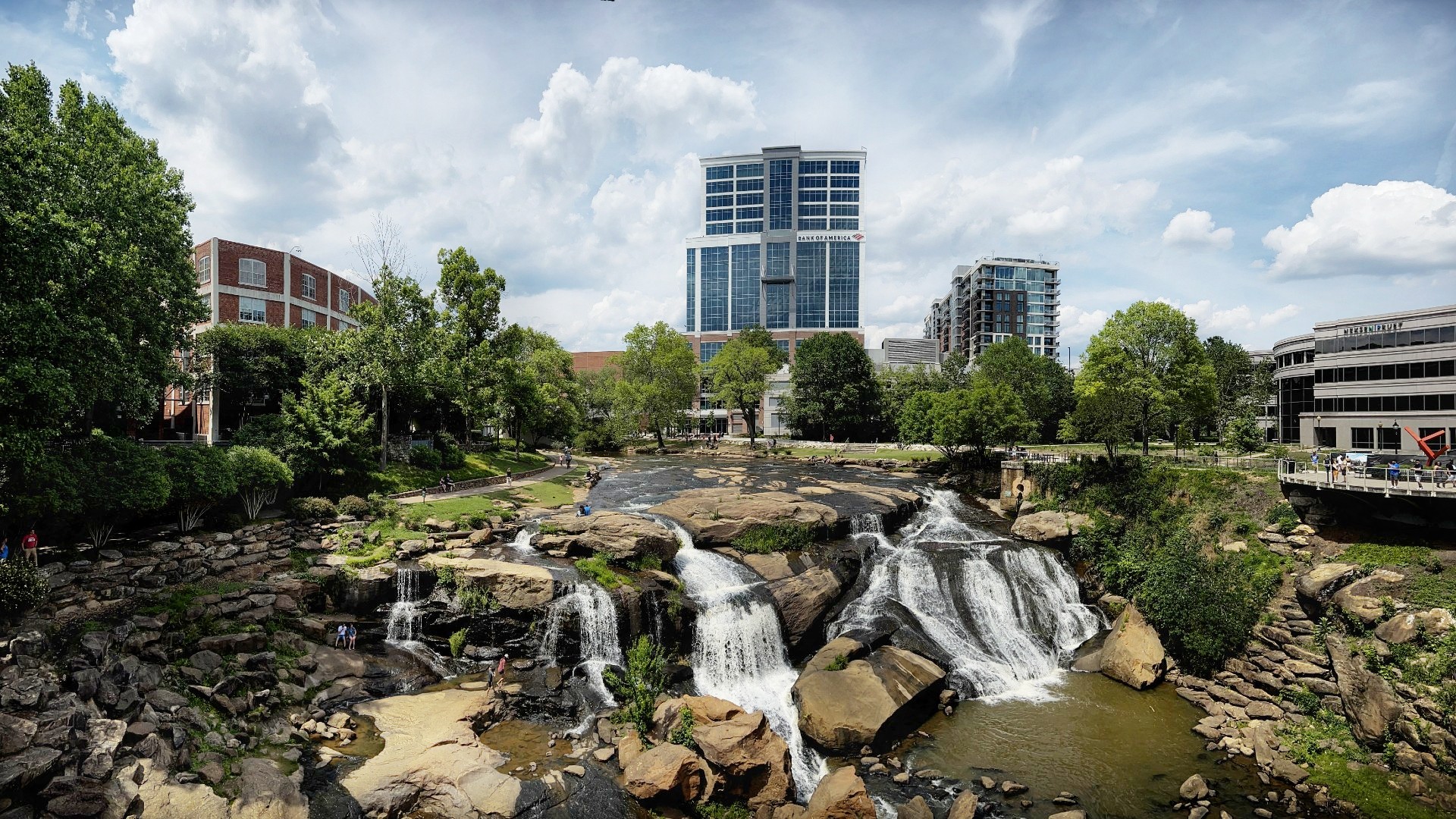 Park area of a downtown city with a cascading waterfall and green trees