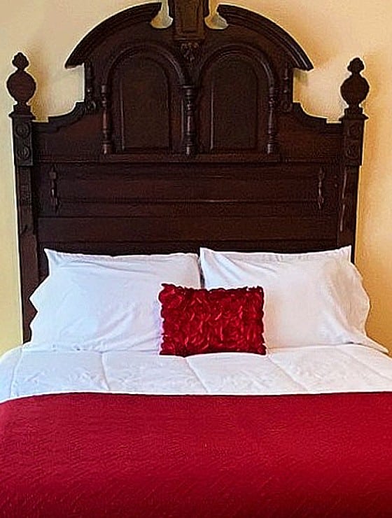 Queen bed in red and white with large antique mahogany headboard